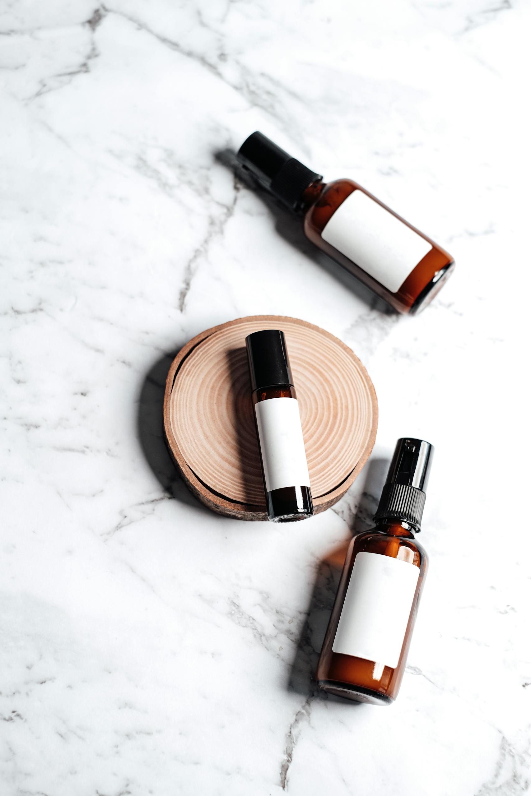 A set of skincare product bottles displayed on a marble surface with a wooden accent.