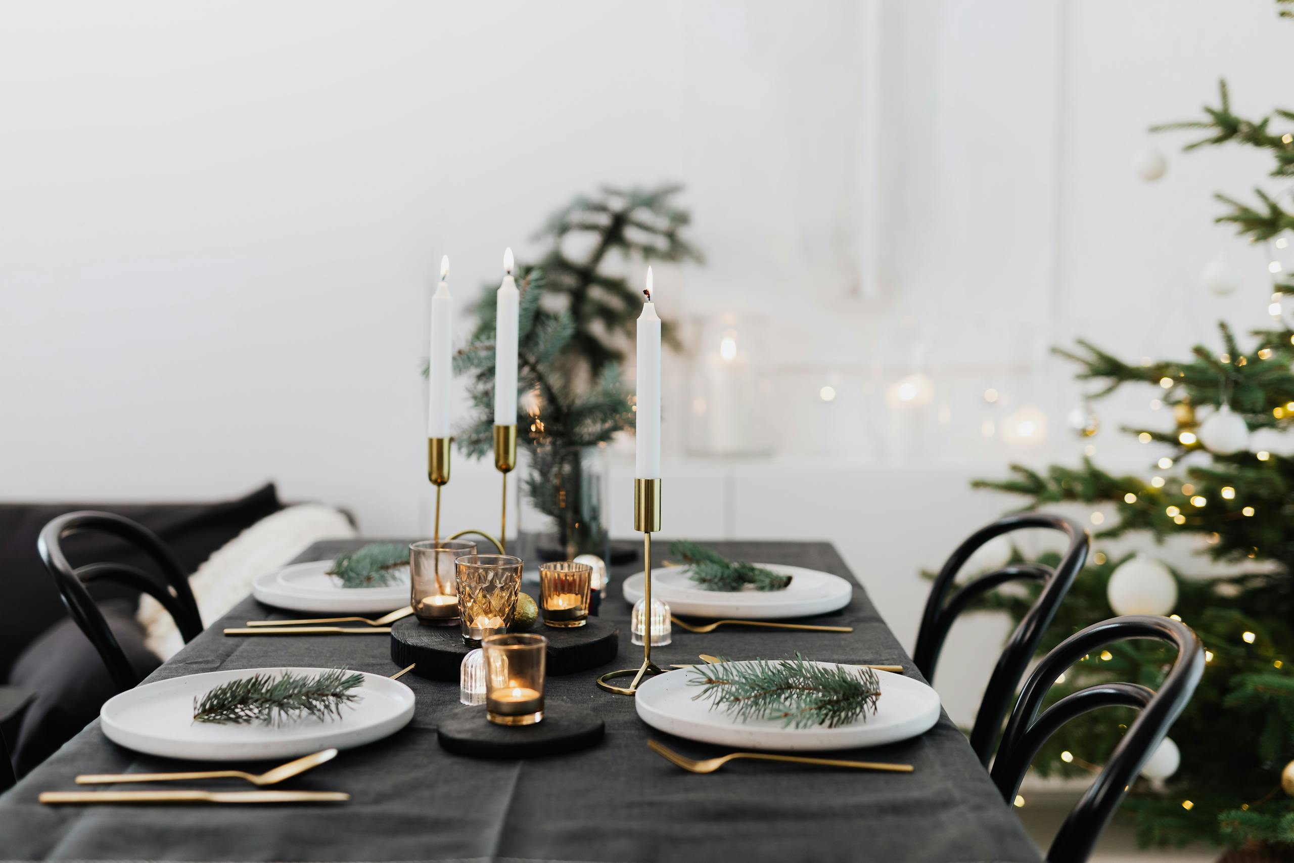 Festive Christmas table setting adorned with candles, pine branches, and elegant tableware hosting must haves.