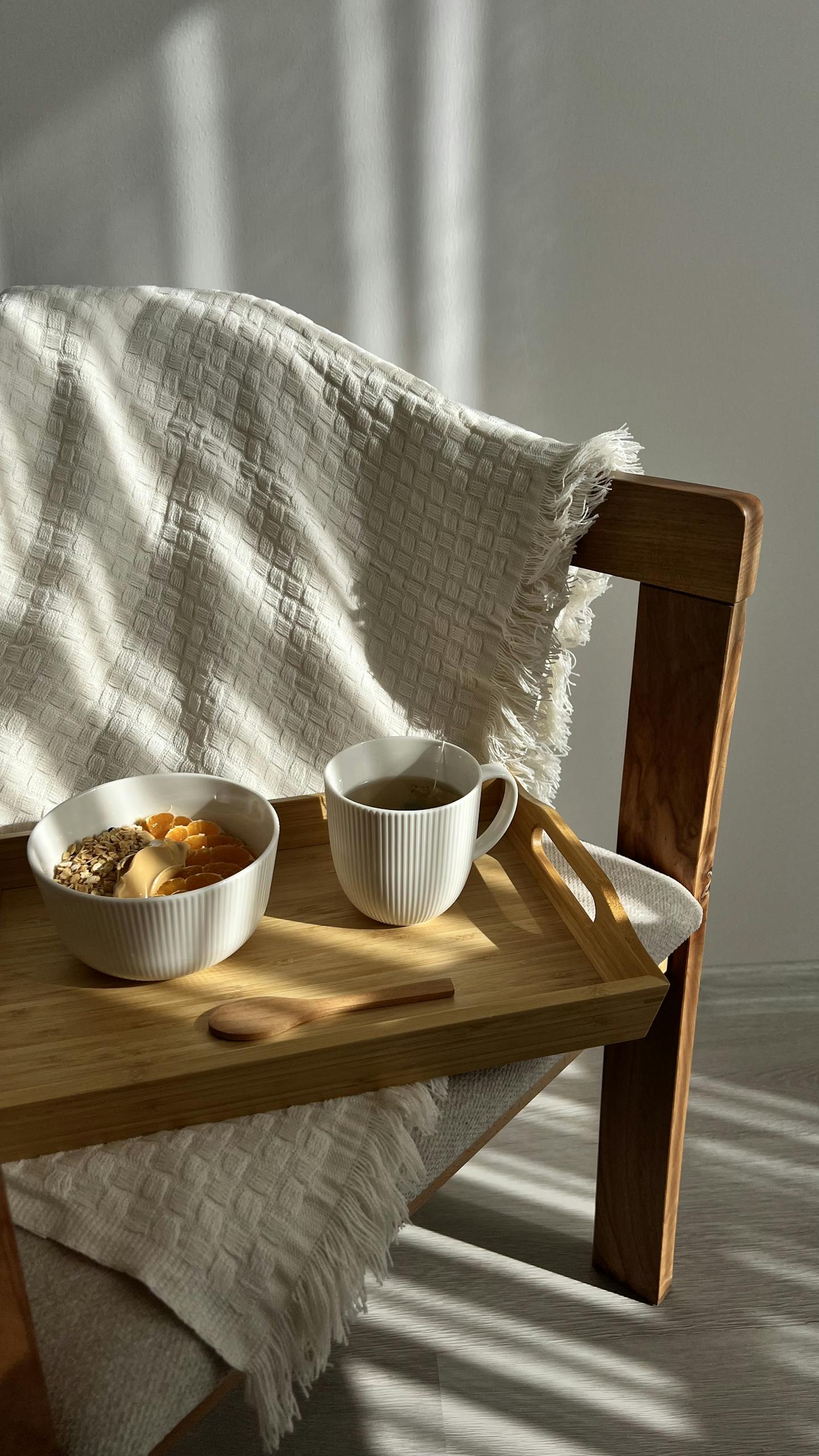 Warm cozy fall morning setting featuring a breakfast tray with coffee and oatmeal on a wooden chair.