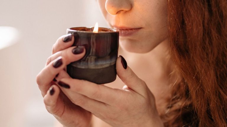 candle gift ideas for the candle snob holding a candle in a ceramic vessel to her nose