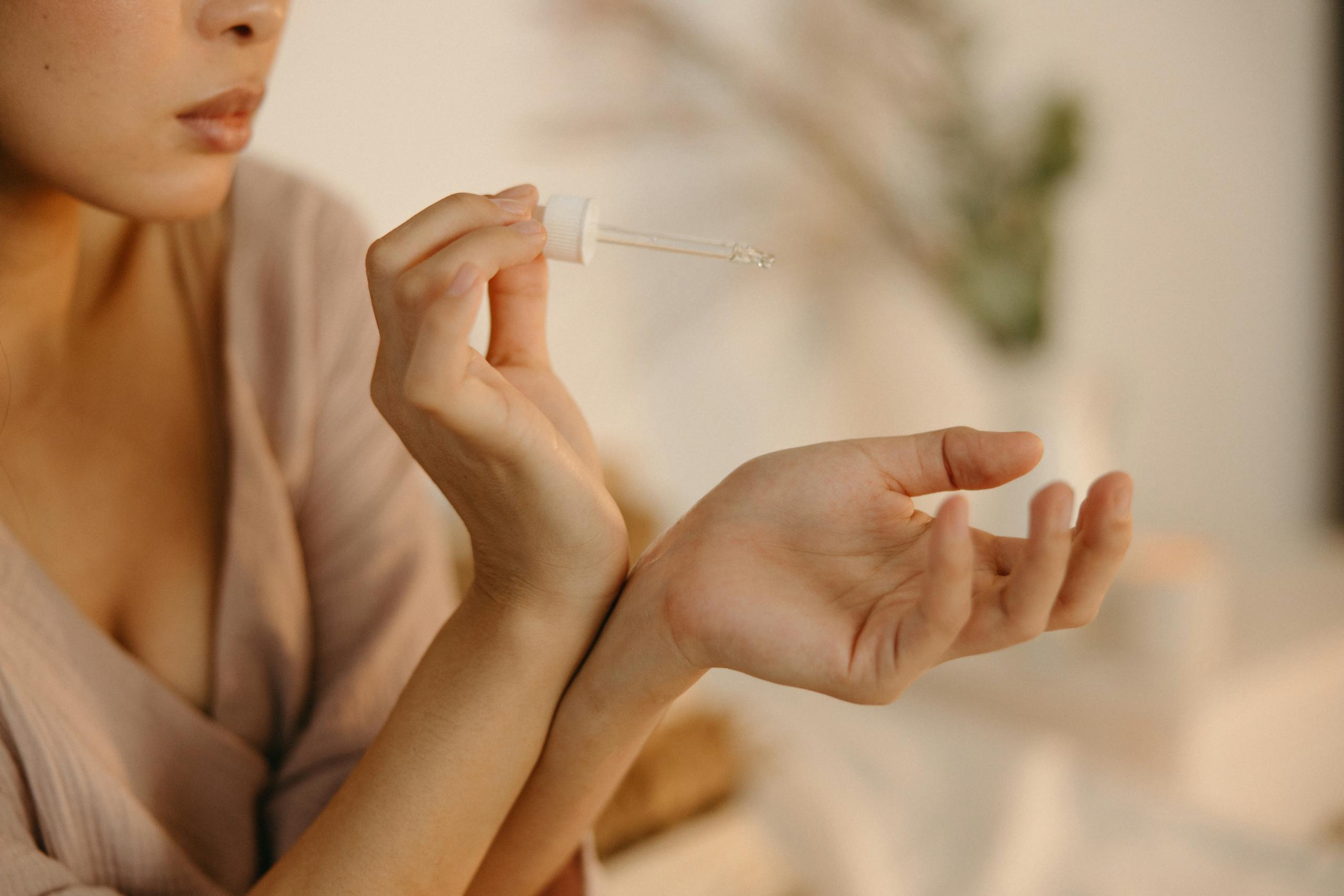 A woman applying vanilla perfume on her wrist in a cozy home setting.