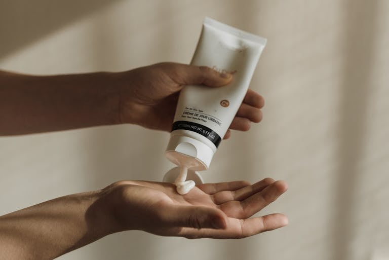 Close-up of a woman squeezing hand cream onto her hand, emphasizing a pretty hands winter hand care routine.