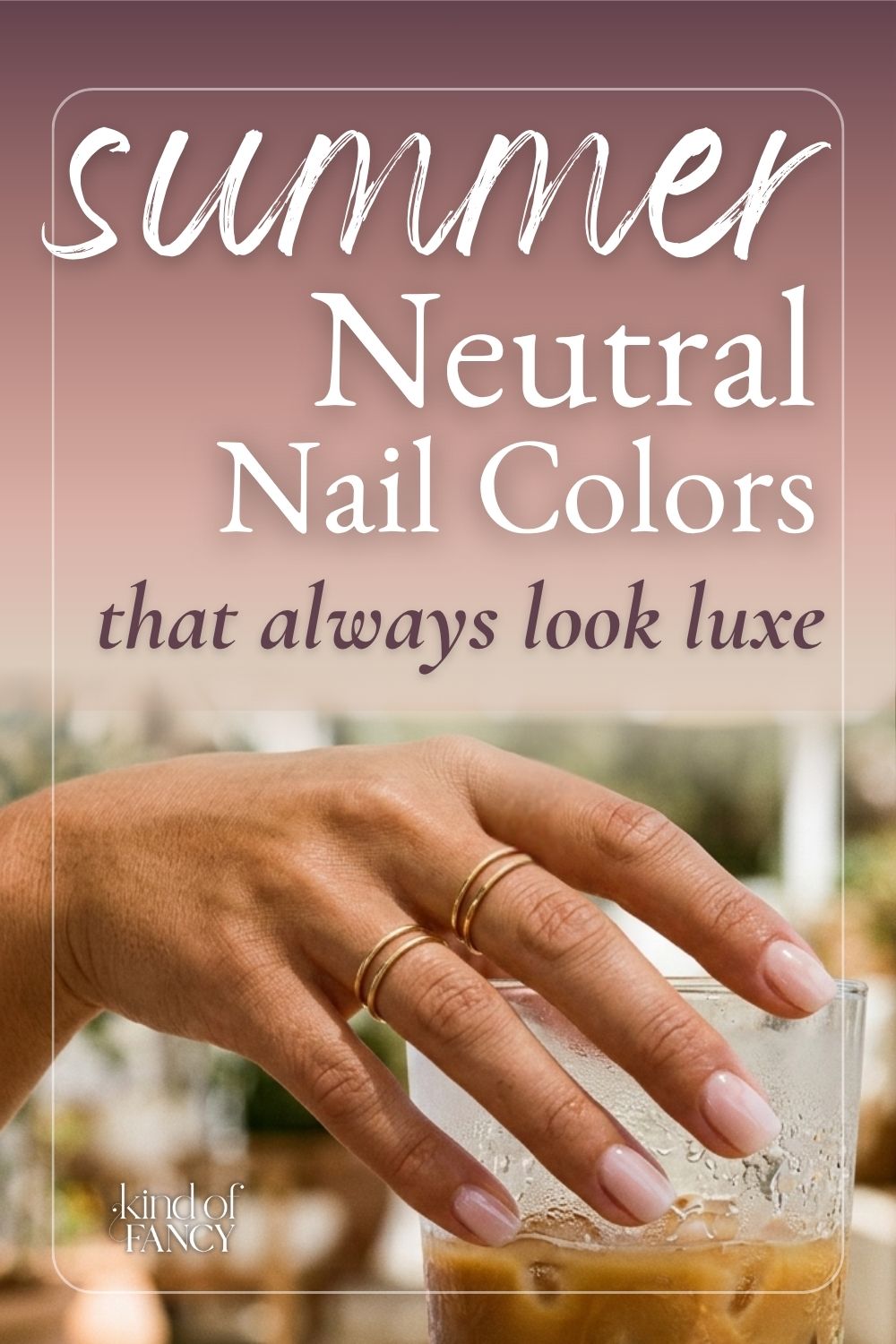 Close-up of a woman's hand with sheer neutral summer nails in glossy milky pink finish, holding a iced latte on a sun-drenched Mediterranean terrace.