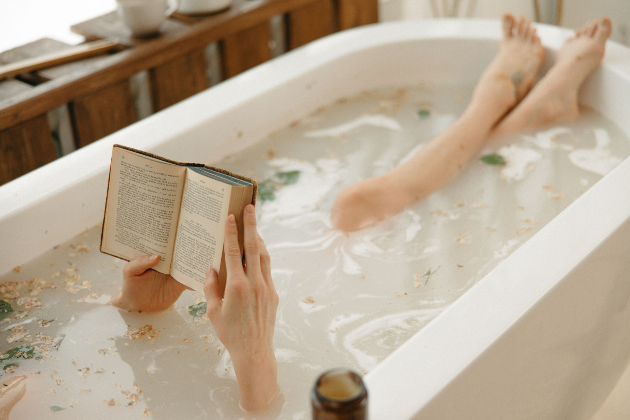 Cozy indoor scene of a woman reading in a bathtub surrounded by warm light with gifted luxury bubble bath
